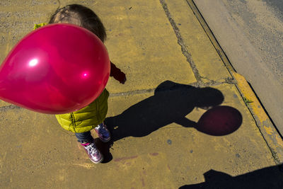 High angle view of child holding balloon on street