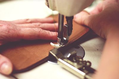 Close-up of tailor stitching leather on sewing machine