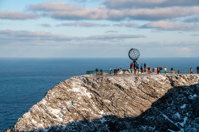 People by sea against sky