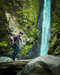 Man standing against waterfall in forest