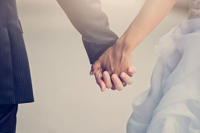 Cropped image of bride and bridegroom holding hands during wedding ceremony