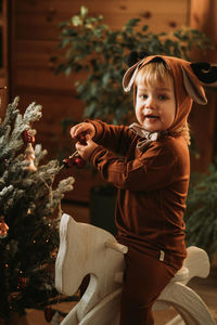 Toddler baby boy in rudolph reindeer costumes decorating christmas tree christmas tree