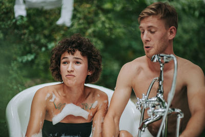 Portrait of shirtless man and woman looking at camera