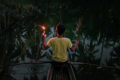 Rear view of boy holding friends at night