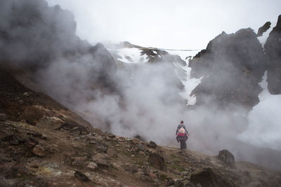 Rear view of woman standing at active volcano