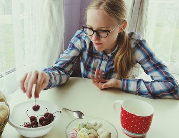 Young woman eating cherries at home