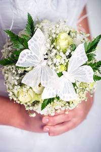 Midsection of bride holding butterflies on bouquet