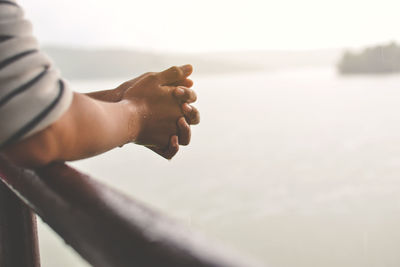 Close-up of woman hand by sea against sky