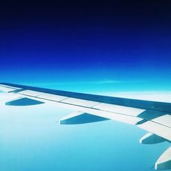 Cropped image of airplane flying over blue sky