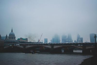 Bridge over river in city against sky