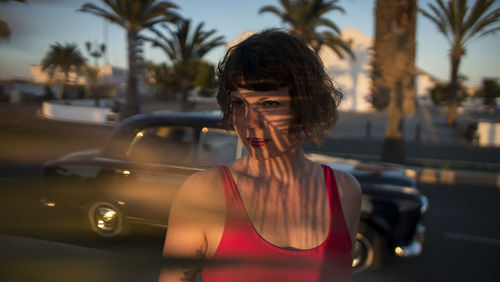 Woman standing against car