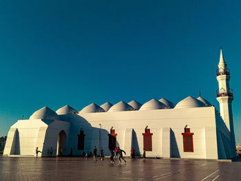 Group of people in front of building against clear blue sky