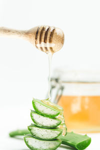 Close-up of aloe vera slices and honey by jar on table