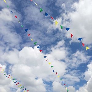 Low angle view of colorful buntings hanging against cloudy sky