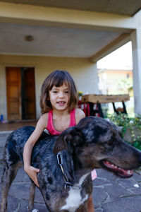 Little girl hugs her grey dog standing next to her
