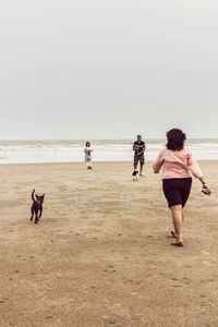 Rear view of women on beach against clear sky