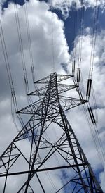 Low angle view of electricity pylon against cloudy sky