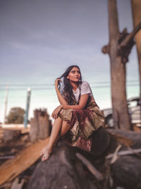 Portrait of woman sitting in sea against sky