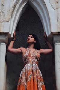 Woman looking up while standing against wall