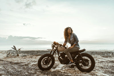 Portrait of young woman riding bicycle on beach