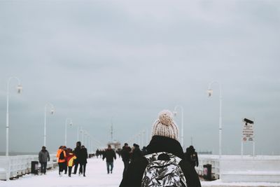 Rear view of person on snowy bridge against sky