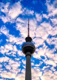 Low angle view of communications tower and building against sky