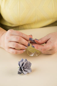 The master sculpts a petal from polymer clay to create a decorative flower.