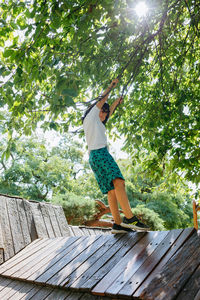 Standing on playground girl in casual clothes playing with tree branches