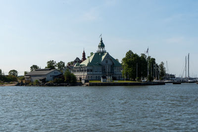 View of buildings by river against sky in city