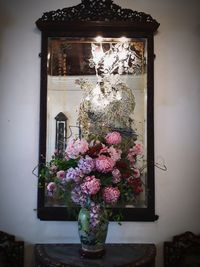 Flower vase against window at home