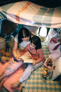 Low angle view of girl and woman lying on bed