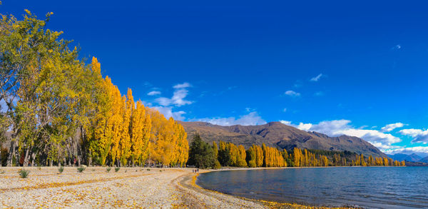 Scenic view of lake by mountain against blue sky