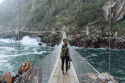 Rear view of woman on footbridge over water