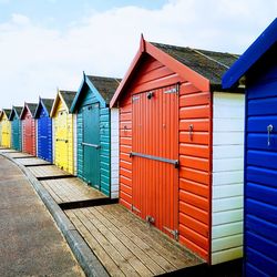 Multi colored huts on beach by building against sky