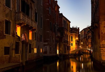 Canal amidst buildings in city at dusk