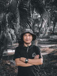 Portrait of young man standing against trees