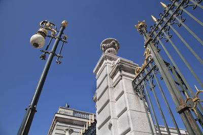 Low angle view of cross amidst buildings against clear blue sky