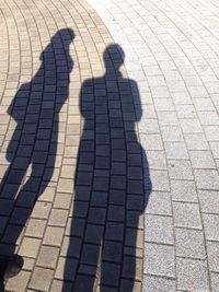 High angle view of couple shadow on tiled floor