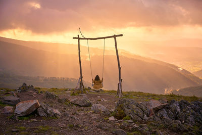 Rear view of woman sitting on swing against sky