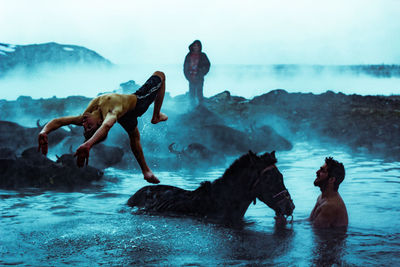 People swimming in sea against sky