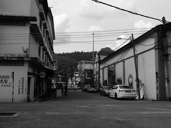 Cars on street by buildings in city against sky