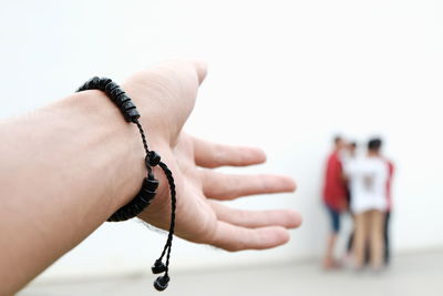 Cropped image of hand against people standing by wall