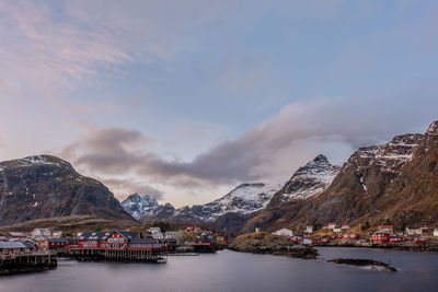 Buildings by sea and mountains against sky