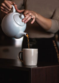 Midsection of man pouring coffee in cup