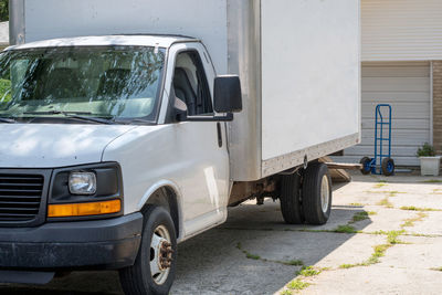 Moving van waits in the driveway with a blue dolly ready to load up for a home move