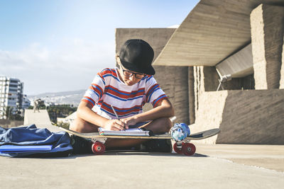 Rear view of boy sitting on seat against sky