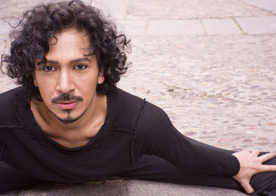 Portrait of man stretching legs on footpath