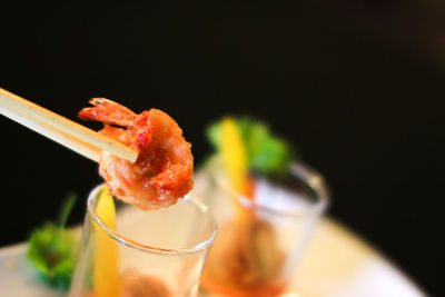 Shrimp on chopsticks over glass