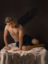 Full length of man wearing wings sitting on table