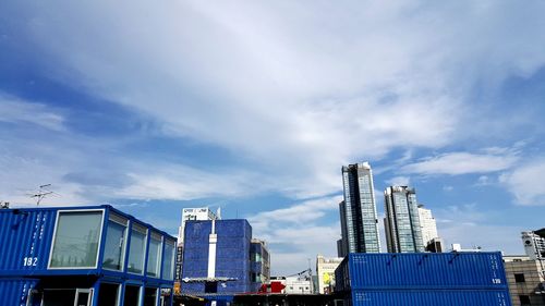 Low angle view of modern buildings against cloudy sky